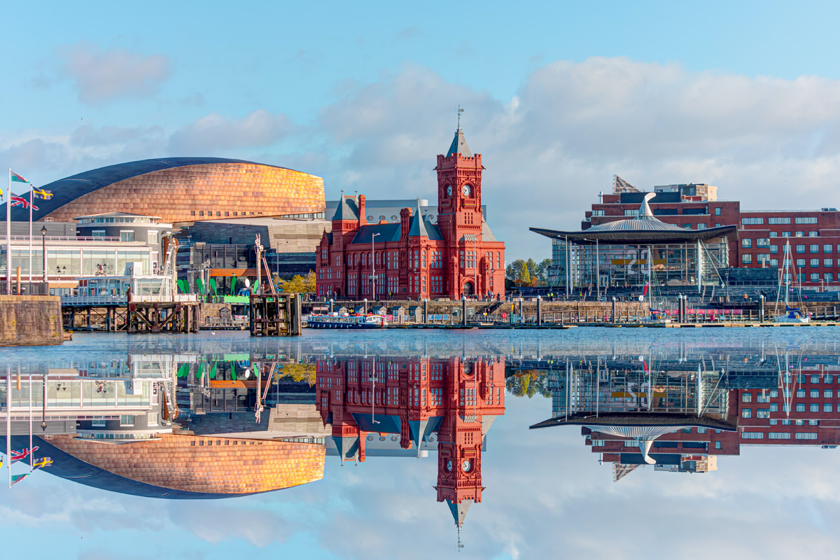 Cardiff, Wales. The Pierhead building, Senedd building and Millennium Centre, relected in Cardiff Bay in summer.