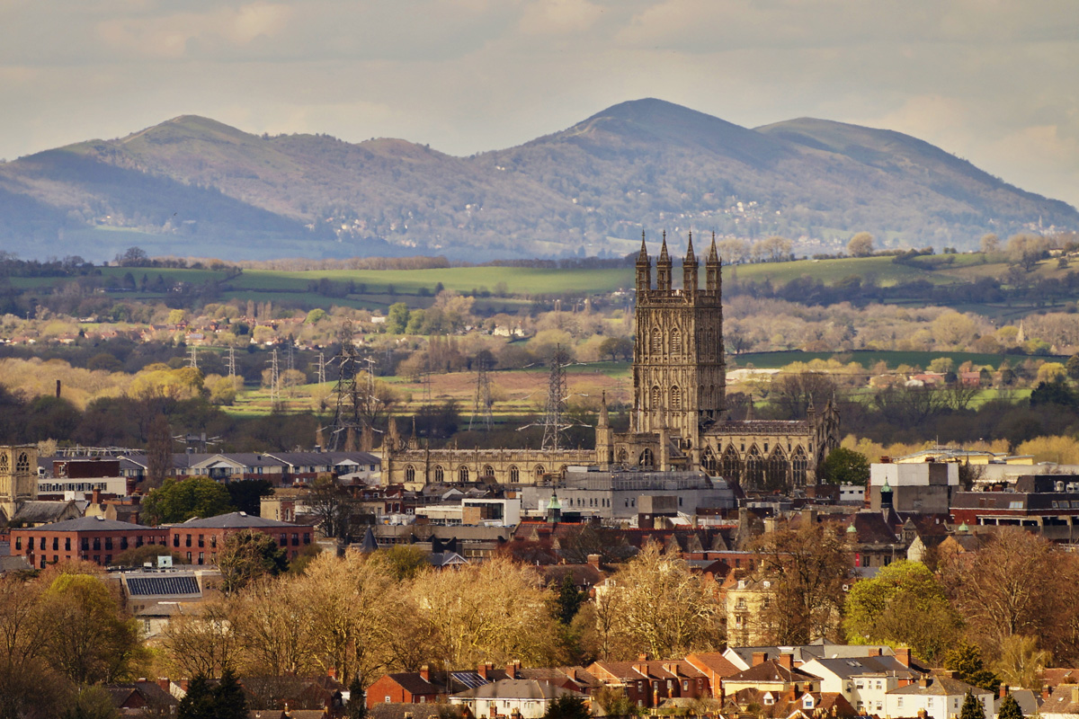Gloucester Cathedral in the city of Gloucester sits set against rolling hills and countryside. Photograph taken in autumn.
