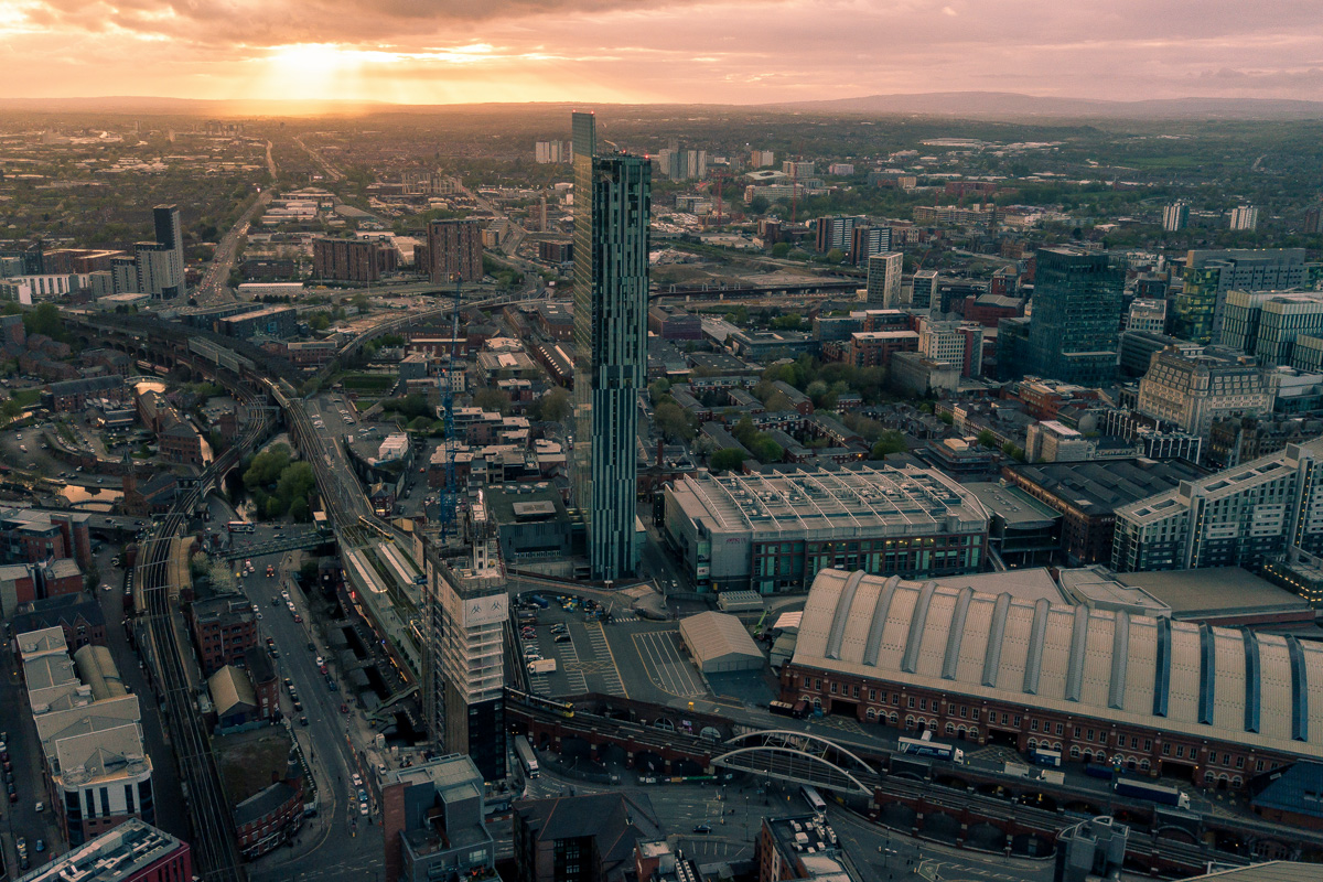 An aerial view of the city of Manchester at sunset. Beetham Tower (the Hilton Hotel) rises out of the city in the centre of the image.