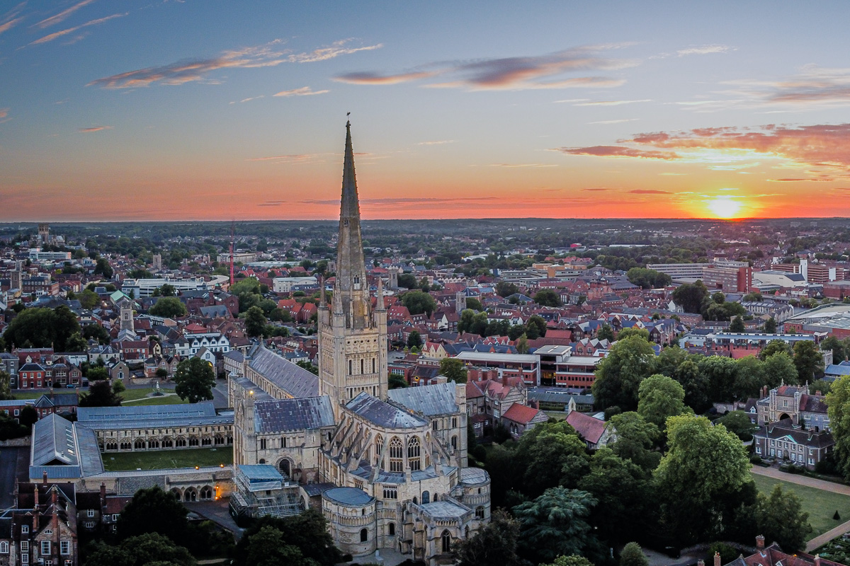 An aerial view of Norwich Cathedral with the city of Norwich in the background. Photograph taken as the sun sets.