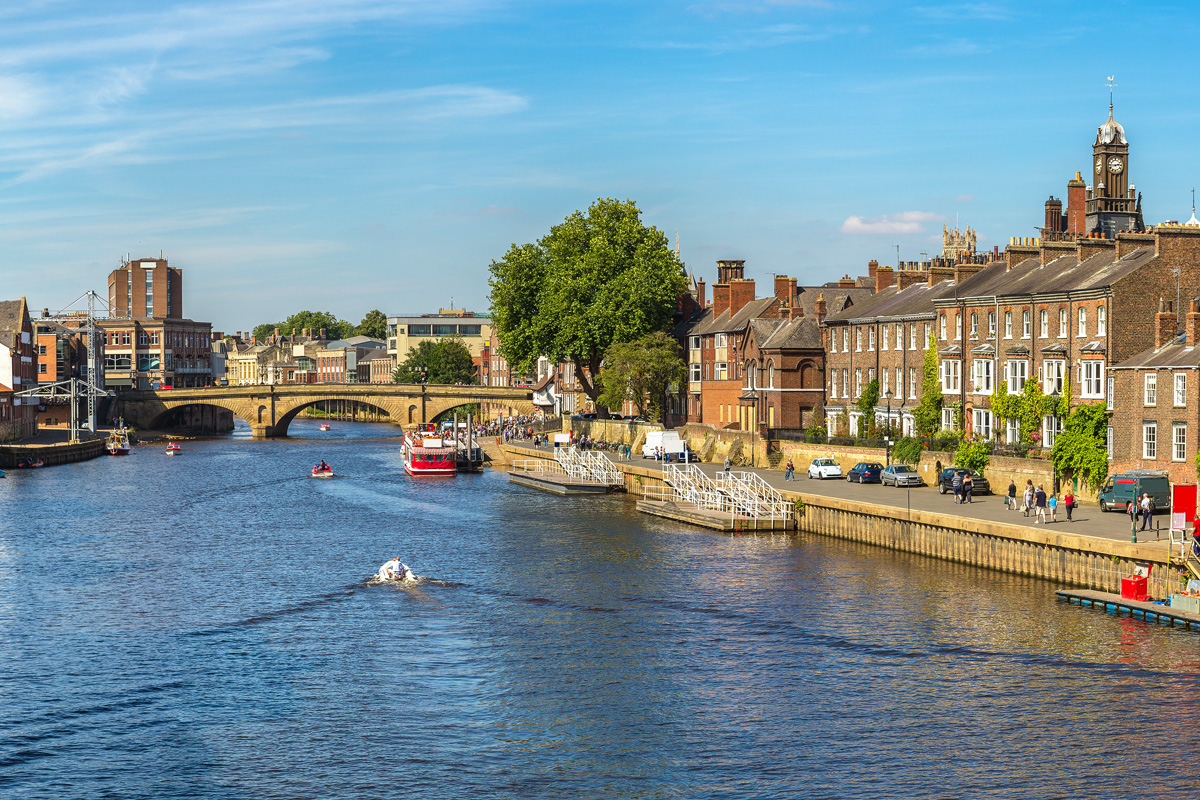 Boats sale down the River Ouse through the historic city centre of York in North Yorkshire. Photograph taken on a beautiful summer day.